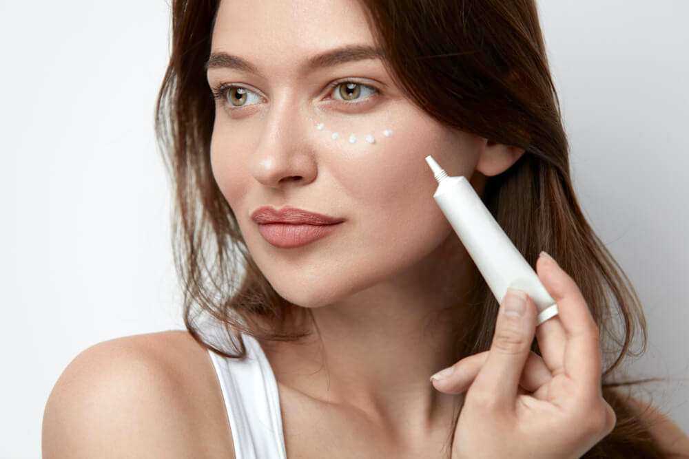 Young woman applying eye cream with an applicator